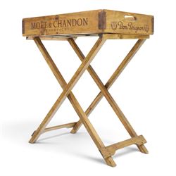 Champagne butler’s tray on stand, the wooden tray printed with champagne bottles and brand names, with cutout handles, raised on a folding stand