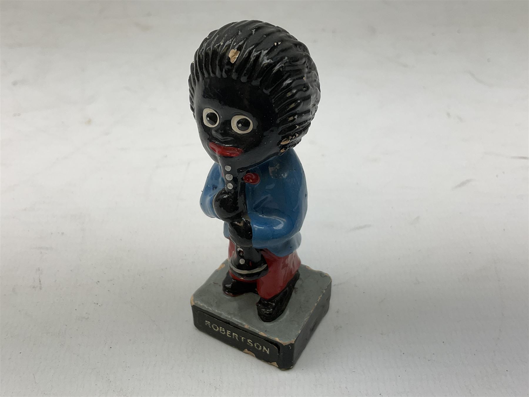 Robinson Jam plaster Golly band, including drummer and singer, H7.5cm

Originally handmade by mothers in Africa for their children from old fabric and cloth, the golly doll was adopted as the mascot and trademark for the Robertson's confectionery brand around 1910 after the company's founder John Robertson visited the US and noticed children playing with them. Robertson's Gollies have been collected by people across the UK and around the world for generations but garnered a contentious image in the 1980s because of links to racism. The trademark was removed from Robertson's branding in 2001.