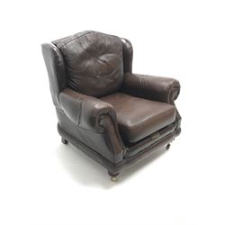 Thomas Lloyd wing back armchair upholstered in a brown leather, turned supports on castors