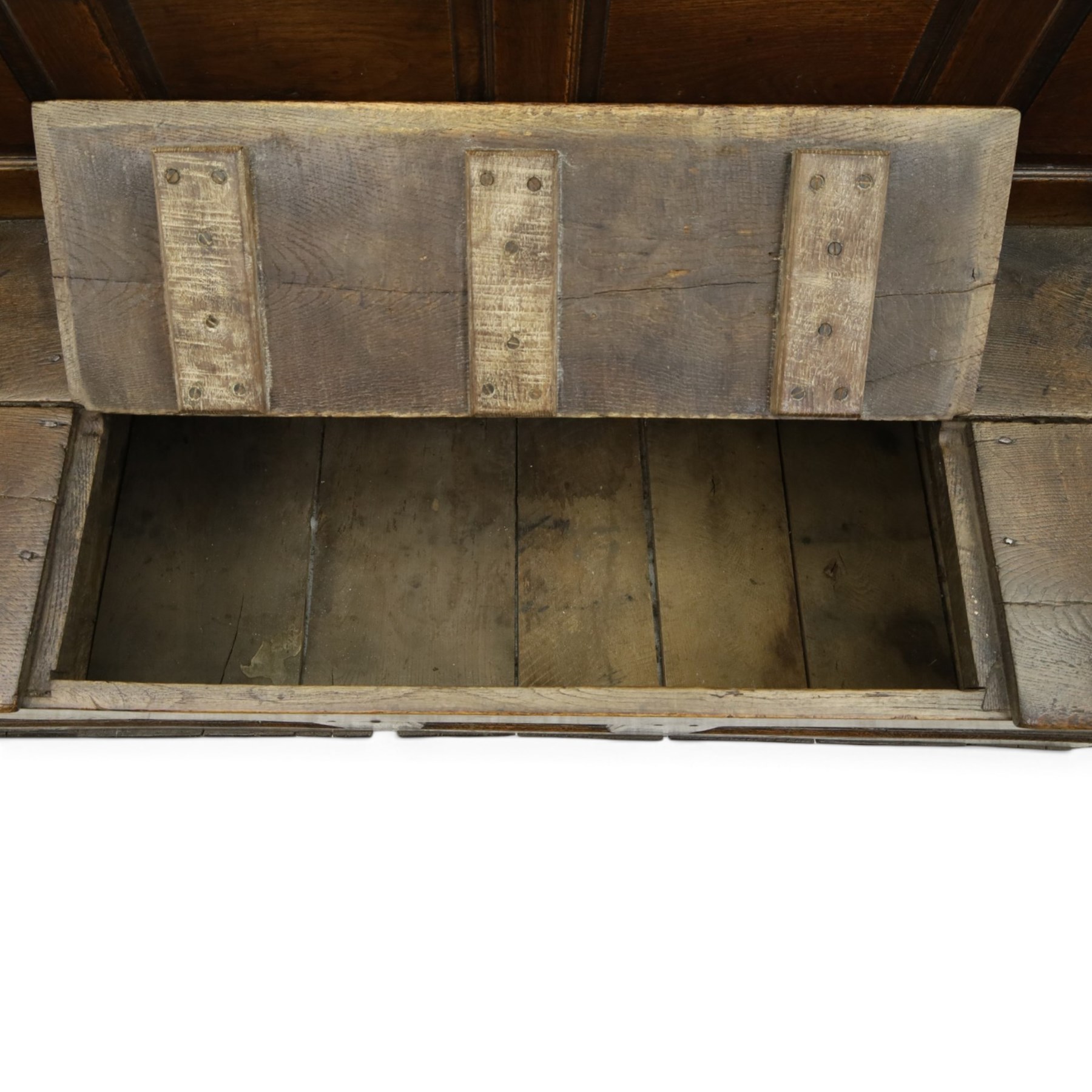 18th century oak high-back settle or hall bench, the panelled back and arm terminals over a hinged box seat, panelled front on short stile feet