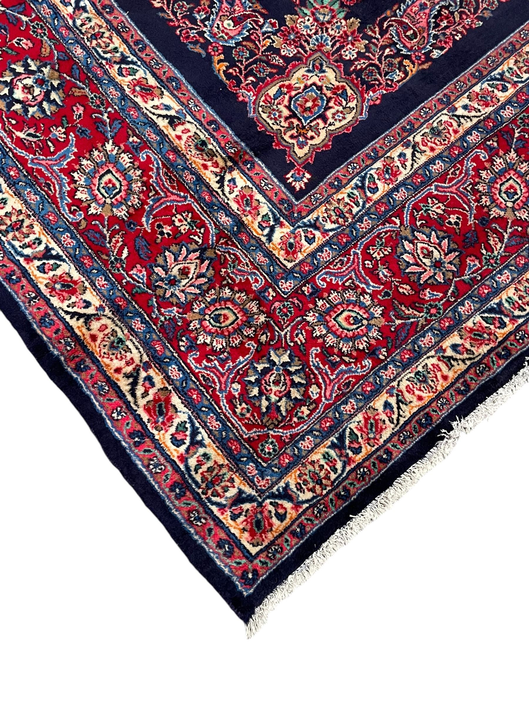Persian Hamadan indigo ground carpet, the field decorated with central rectangle and outer band, overall floral pattern with cusped central medallion and surrounding leafy branches with palmettes, the border with scrolling branches decorated with further palmettes, within floral pattern guard stripes