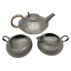 Archibald Knox for Liberty & Co Tudric pewter three piece tea service, comprising teapot with woven reed handle, single handled open sucrier, and milk jug, each with planished finish and detailed with honesty flowers, each impressed beneath Made in England Tudri Pewter 0231 
