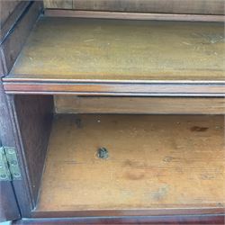 Early 19th century figured mahogany bureau bookcase, projecting splay moulded cornice over three adjustable shelves enclosed by two glazed doors, fall front revealing pigeonholes, cupboard and drawers, pull-out strays with scroll carved terminals, double cupboard with two panelled doors, on turned feet 