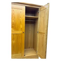 Contemporary light oak double wardrobe, projecting cornice over two panelled doors enclosing hanging rail and shelf, above full-width drawer, on shaped stile supports