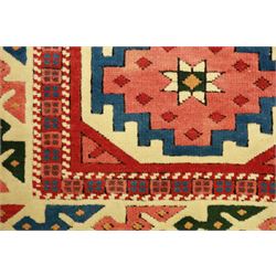 Anatolian Soumak rug, ivory ground decorated with a grid of eight octagonal medallions in terracotta red outlined in blue, centered with a star motif in vertical rows, framed by a series of geometric borders in ivory, green, and blue, incorporating hooked devices and stylized lozenges and stripped end panels, with signature at either end 