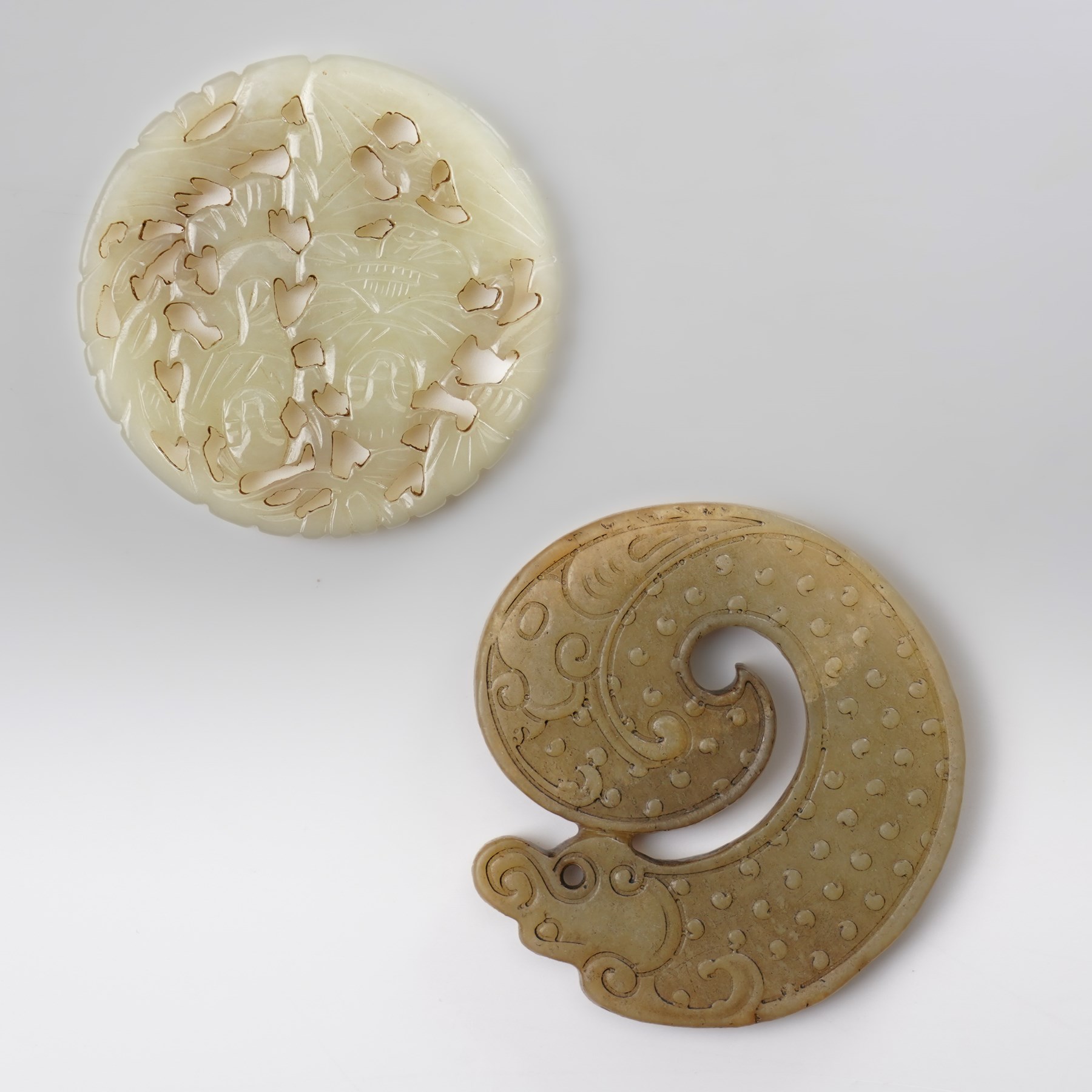 Two carved greenstone roundels, one carved with figures, the other with a dragon, D5.5cm (2)