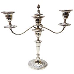 Modern silver twin branch candelabra, the oval filled and part fluted base leading to a faceted tapering stem with faux capital supporting a faceted urn shaped capital with removable nozzle and snuffer with flambeau finial, and two scrolling branches with conforming capitals and nozzles above drip pans, hallmarked Mappin & Webb Ltd, Sheffield 1968, H32cm
