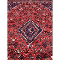 Persian Joshaghan crimson ground rug, stepped lozenge medallion surrounded by repeating foliate lozenge motifs, the border decorated with stylised plant motifs, within geometric guard stripes
