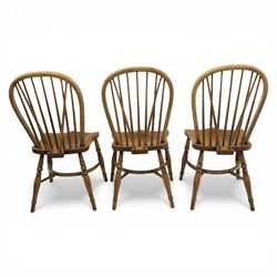 Traditional elm and beech Windsor dining chairs, each with hoop back and turned spindles over a shaped solid seat fitted with loose floral upholstered cushions, raised on turned tapering supports united by crinoline stretchers