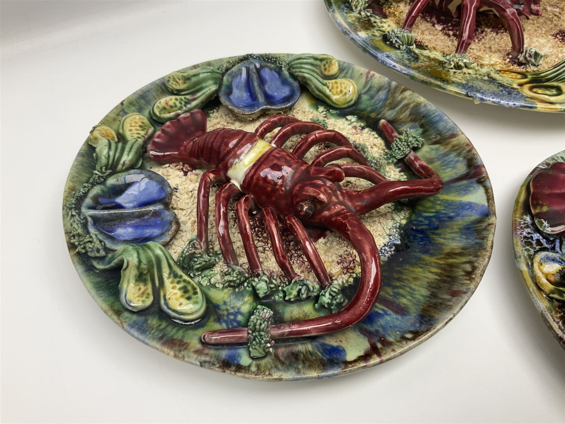 Five 20th Century Portuguese Palissy style Majolica wall plates, all depicting crustaceans to the centre modelled in relief surrounded by encrustations and shells, both with impress marks beneath, largest D29cm
