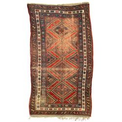 Kurdish crimson ground rug, the field decorated with four lozenge medallions, triple band border decorated with stylised flower heads