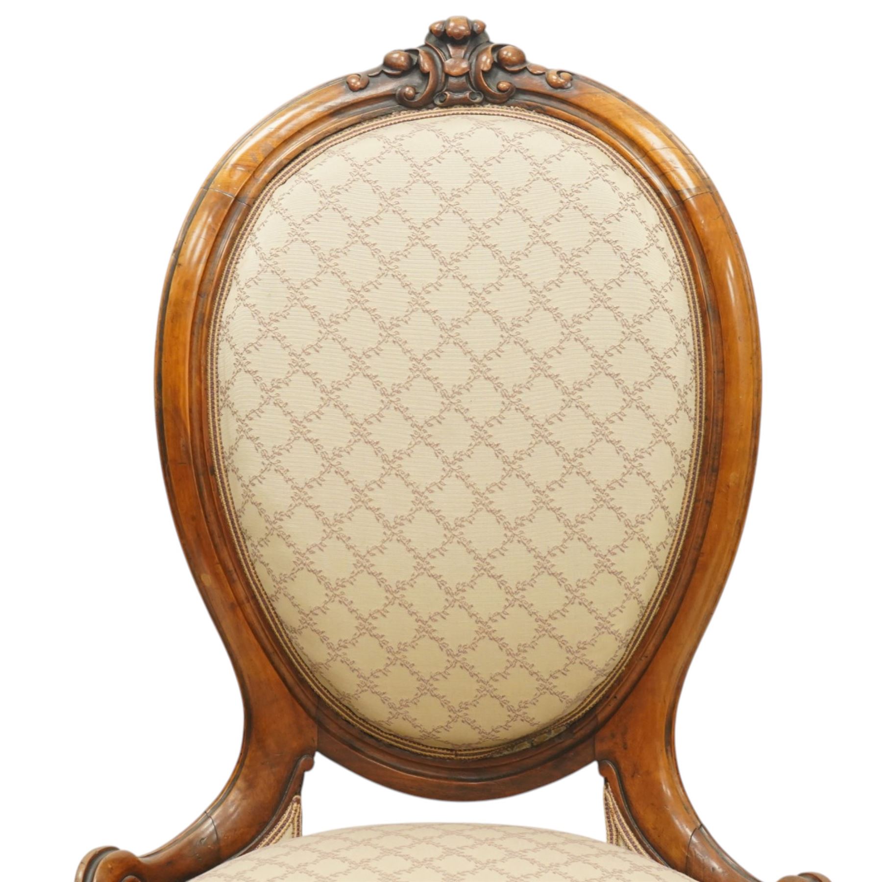 Pair of Victorian walnut framed ladies salon nursing chairs, oval cameo back with carved cartouche carved cresting rail, sprung seat upholstered in foliate patterned ivory fabric, shaped apron carved with scroll and cartouche decoration, on cabriole supports with moulded flower knees, retailed by David Hick Interiors, Jersey