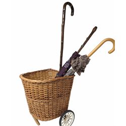 Pull along wicker basket on wheels, with cane handle, together with a silver mounted wooden umbrella and a one other umbrella, basket inlcuding handle H103cm