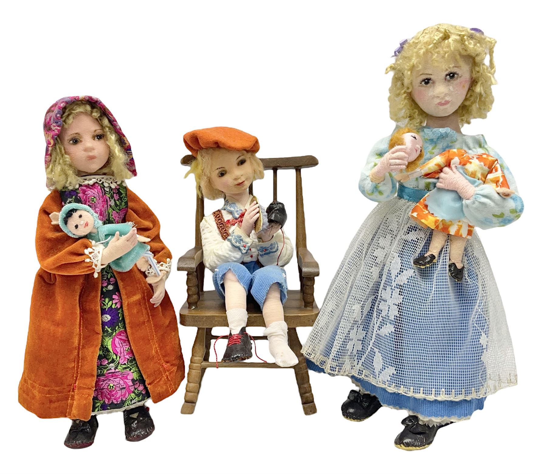 Anna Meszaros Hungary - three hand made needlework figurines - 'The Cobbler' as a child seated in a wooden rocking chair working on a removed boot H24cm; young girl standing crying holding a doll with broken head H32cm; and young girl in long dress and bonnet standing holding a doll H27cm (3)  Auctioneer's Note: Anna Meszaros came to England from her native Hungary in 1959 to marry an English businessman she met while demonstrating her art at the 1958 Brussels Exhibition. Shortly before she left for England she was awarded the title of Folk Artist Master by the Hungarian Government. Anna was a gifted painter of mainly portraits and sculptress before starting to make her figurines which are completely hand made and unique, each with a character and expression of its own. The hands, feet and face are sculptured by layering the material and pulling the features into place with needle and thread. She died in Hull in 1998.