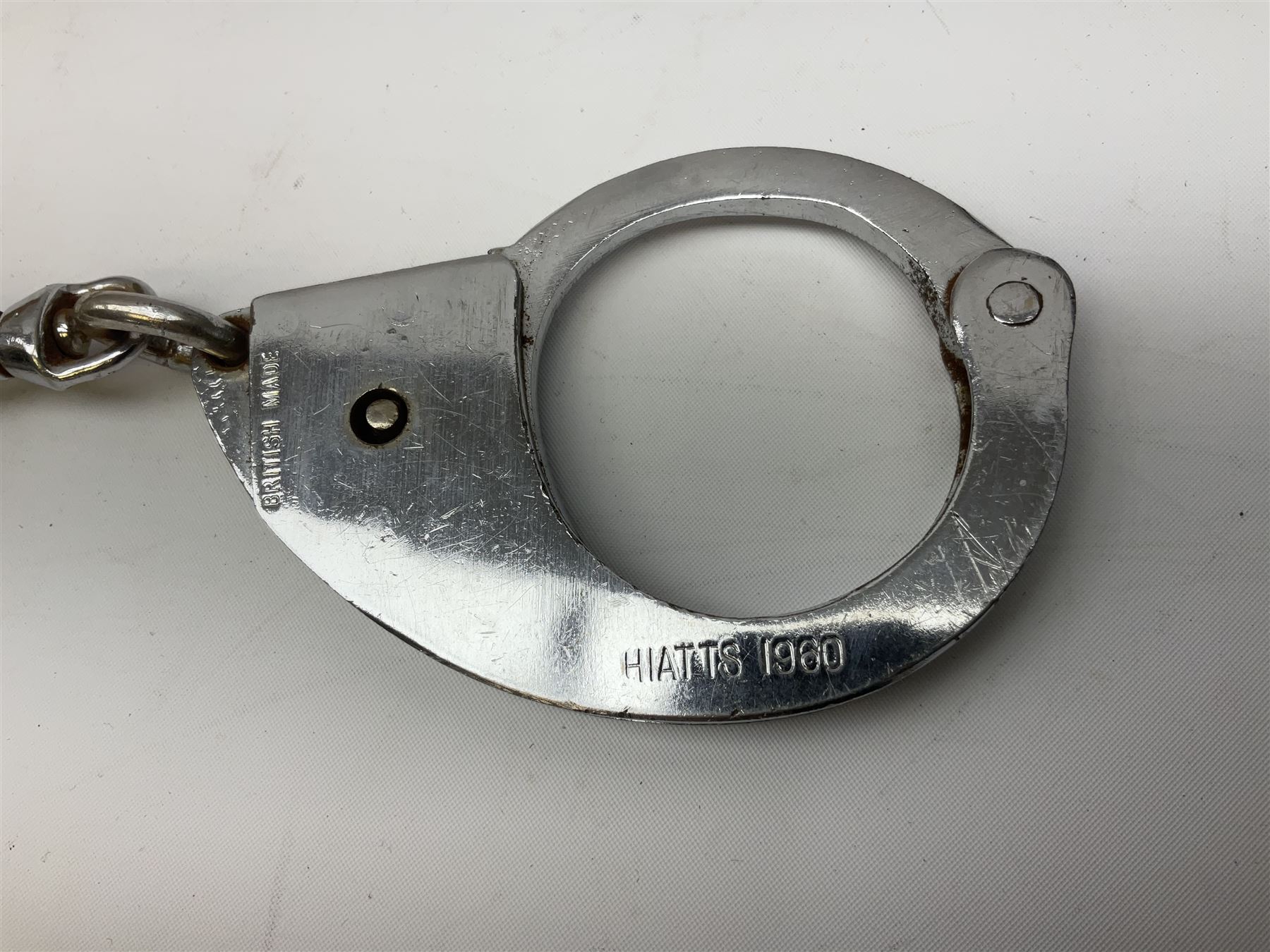 British Transport Police Custodian helmet with Queen's Crown plate; Hiatt & Co ebonised hardwood patrol truncheon; and pair of Hiatts 1960 hand-cuffs (3)