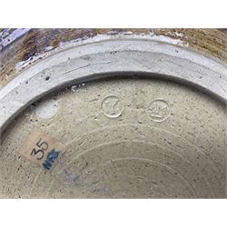 Michael Leach (British 1913-1985) for Yelland pottery; two large glazed stoneware plates with dark brown stylised decoration upon oatmeal ground, together with a jug in merging blue, green and brown, all with impressed marks beneath, largest plate D37cm