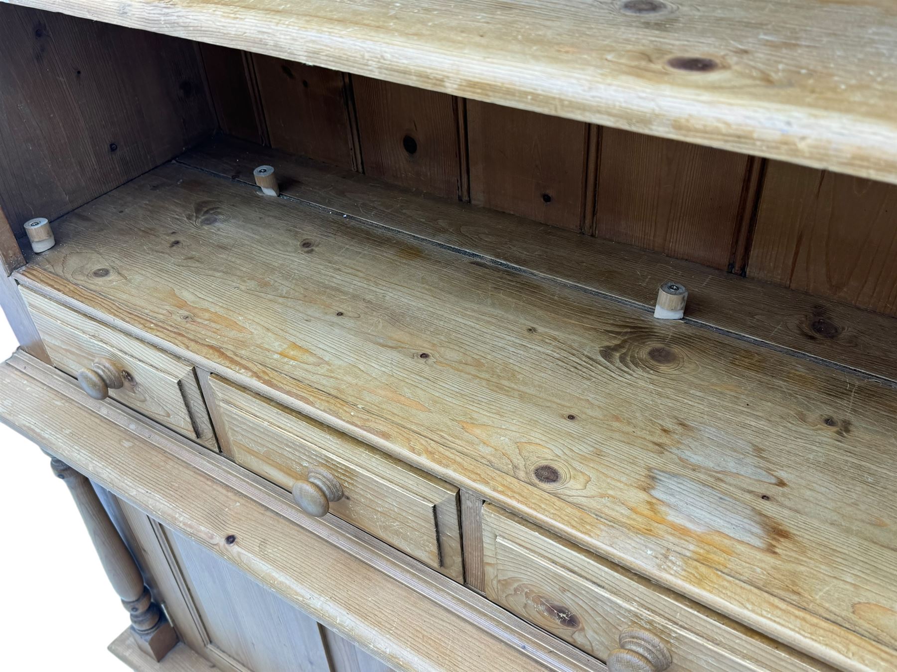 Early 20th century pine kitchen dresser, featuring a hutch with arched top over three open shelves, the base with five drawers over three cupboard doors, turned column supports flanking the doors, scalloped apron base with bracket feet