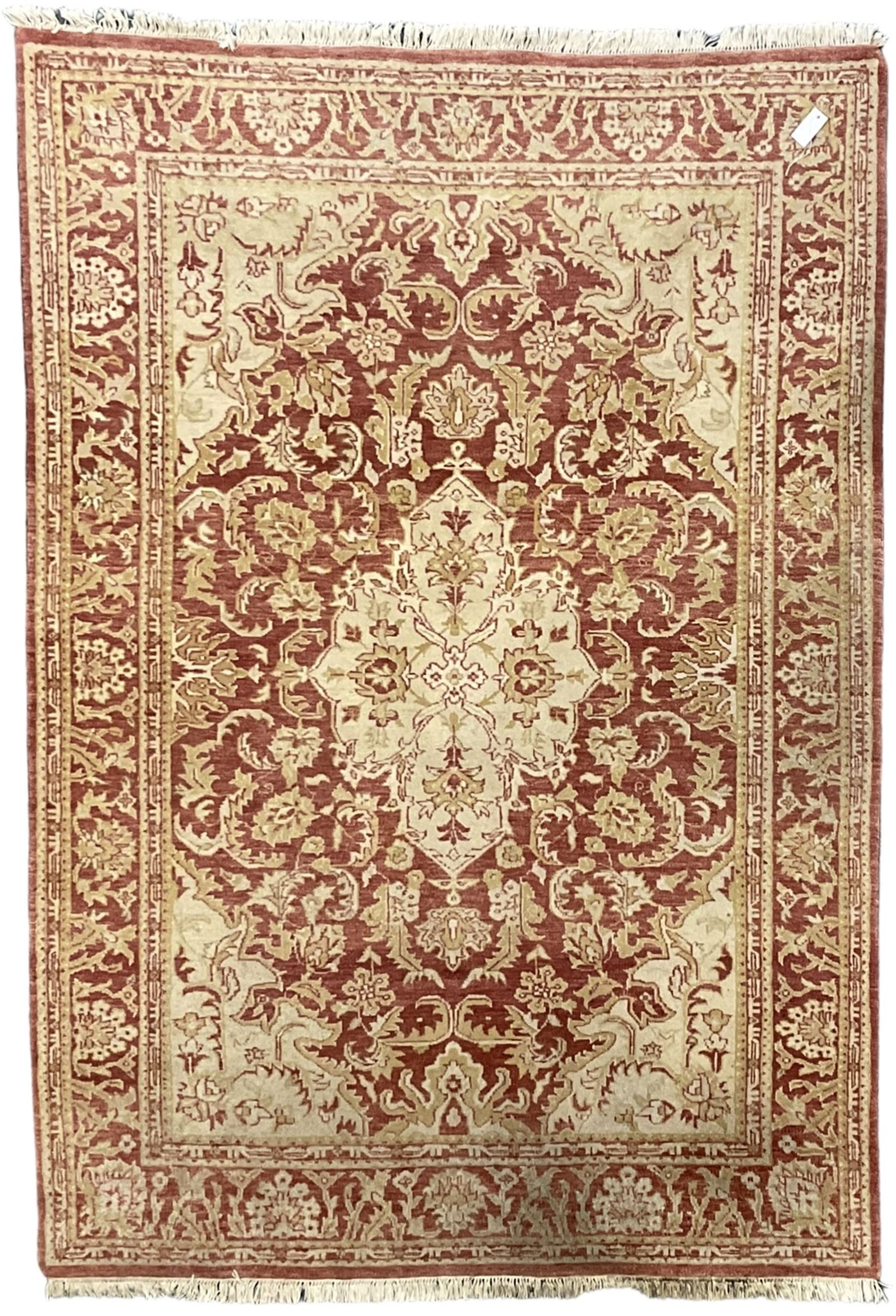Persian design beige and crimson ground rug, the field decorated with interlacing scrolled foliage, repeating border within guard stripes 