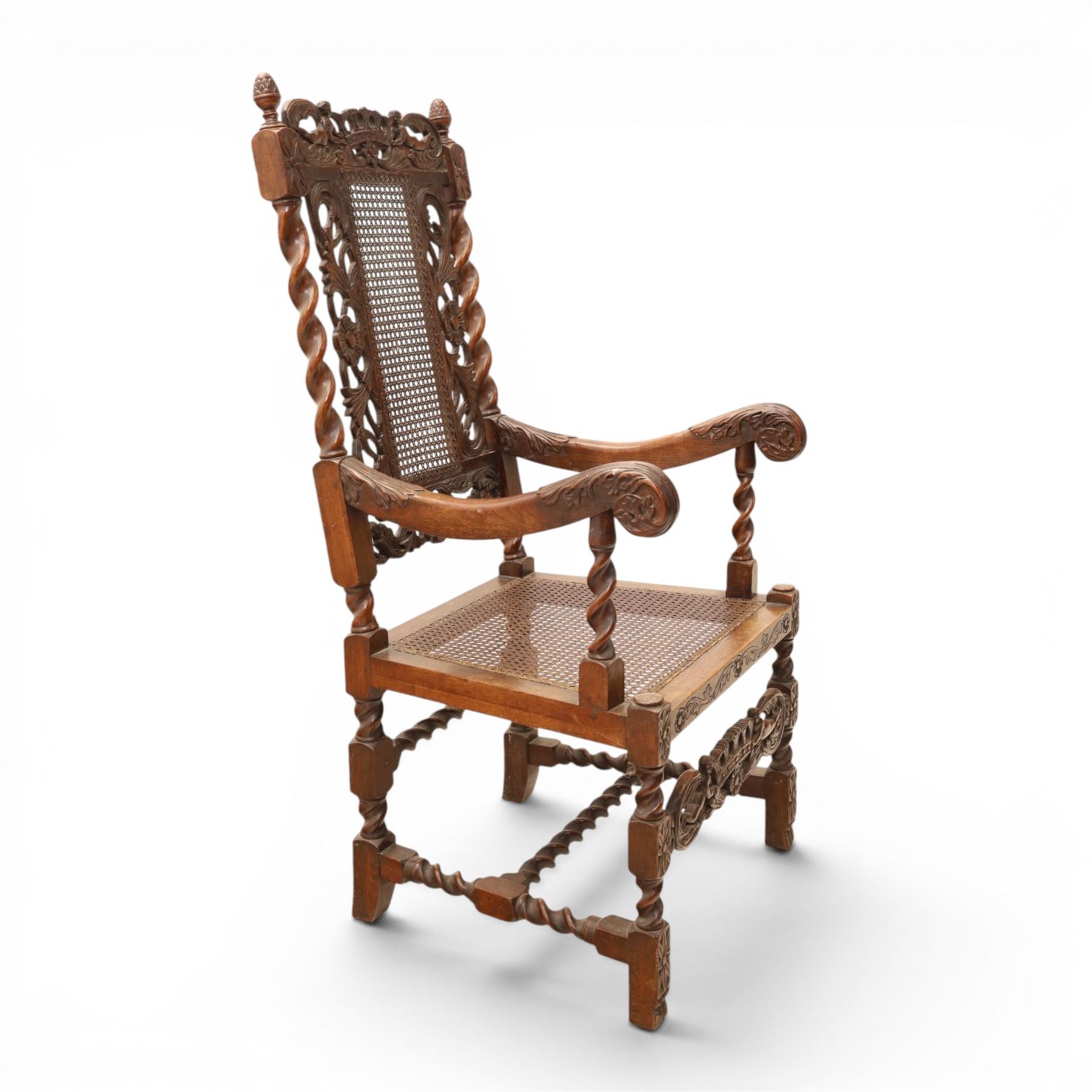 Late Victorian Jacobean Revival oak armchair, the caned back within a pierced and carved foliate frame surmounted by acorn finials, carved scroll arm supports, caned seat, on barley twist supports united by stretchers and carved front rail