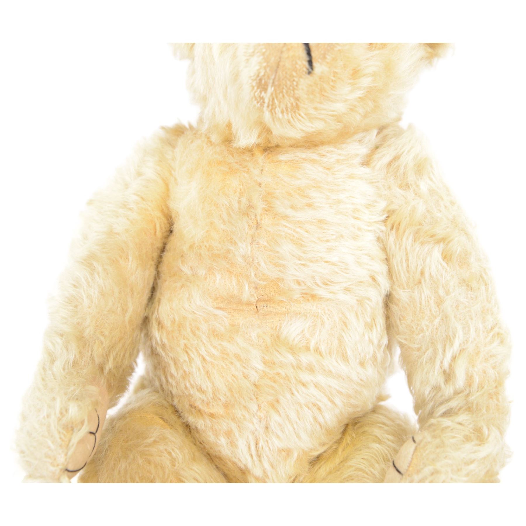 Early 20th century musical teddy bear, with golden mohair head and body, pronounced clipped muzzle, humped back, one eye, black/brown stitched nose, mouth and claws, swivel head and jointed limbs, containing pressure operated musical mechanism, L51cm

Notes by vendor repute: Previously owned by Dame Christian Howard of Castle Howard and given by her in the 1960s to the vendor who was the child of her house keeper.