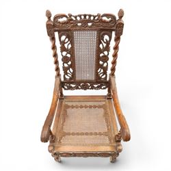Late Victorian Jacobean Revival oak armchair, the caned back within a pierced and carved foliate frame surmounted by acorn finials, carved scroll arm supports, caned seat, on barley twist supports united by stretchers and carved front rail