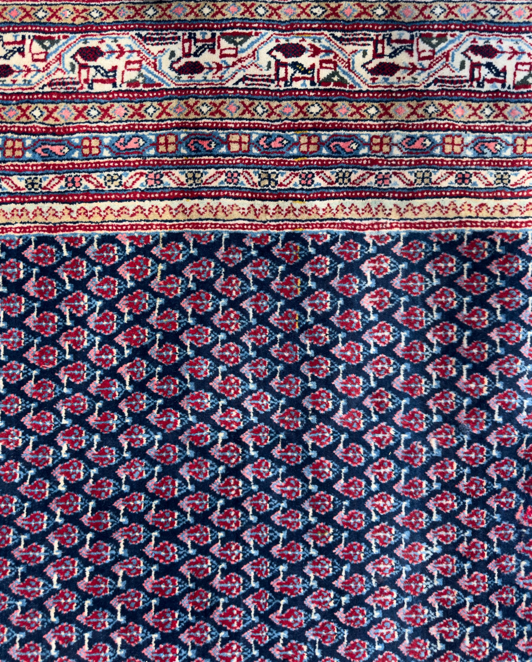 Northwestern Persian Bottehmir hand-knotted carpet, dark indigo field with an all-over design of boteh motifs arranged in diagonal rows, framed by multiple borders, main ivory border with stylized floral sprays between narrow geometric guard stripes, 362cm x 268cm