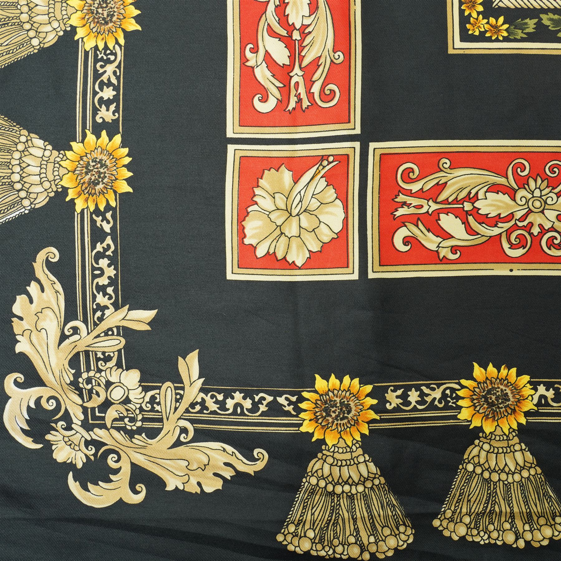 Hermès silk carré scarf, the black ground with central sunflower motif framed by ornate baroque panels and tassel borders in red, gold and yellow tones, signed Hermès Paris to the corner, hand-rolled edges, 90cm x 90cm