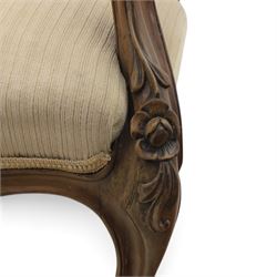 Late Victorian walnut open armchair, the carved shaped cresting rail centred by scrolls and foliage above a padded serpentine back and overstuffed seat upholstered in cream striped fabric, with padded scroll arms on open carved supports, raised on cabriole supports with carved knees and ceramic castors