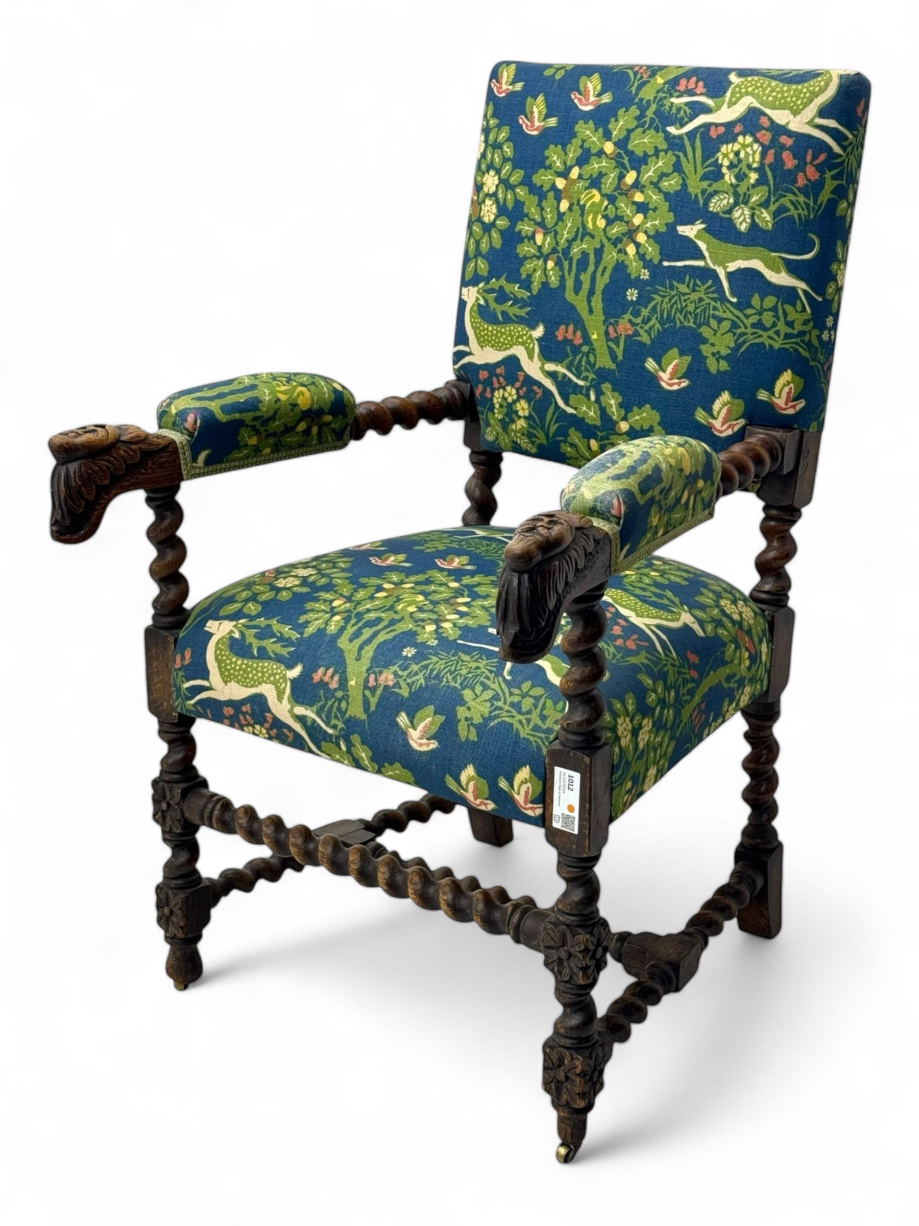 19th century Carolean design oak armchair, upholstered in a vibrant fabric depicting woodland and wildlife scenes, carved lion mask arm terminals, raised on barley twist supports united by H-stretcher