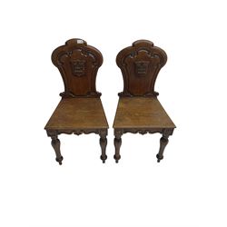 Pair Victorian oak hall chairs, scallop shaped back with carved scrolls and central shield moulding, panel seat over shaped frieze rail, raised on turned supports