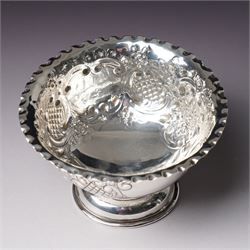 Edwardian silver bowl with embossed decoration on a short pedestal foot D11cm Birmingham 1904 Maker A & J Zimmerman Ltd and a modern silver coaster with turned wooden base D9.5cm Sheffield 2001 (2)