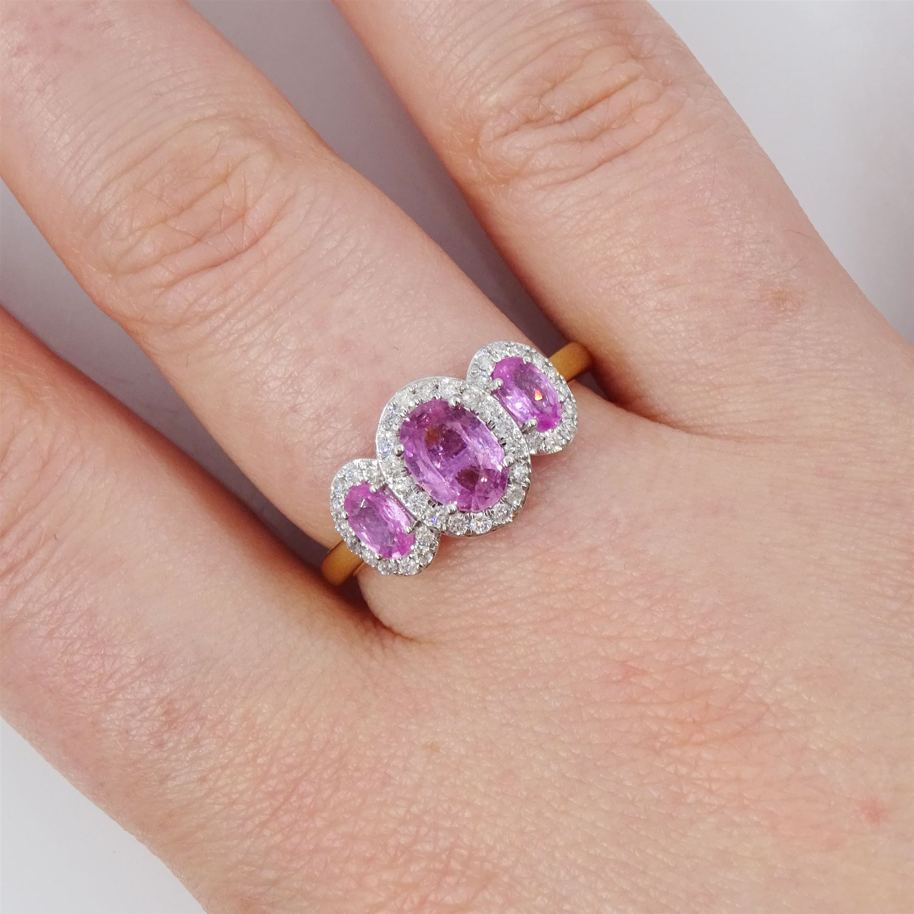 18ct gold pink sapphire and diamond trilogy ring, three oval cut sapphires surrounded by round brilliant cut diamonds, hallmarked, total sapphire weight approx 1.45 carat, total diamond weight approx 0.25 carat