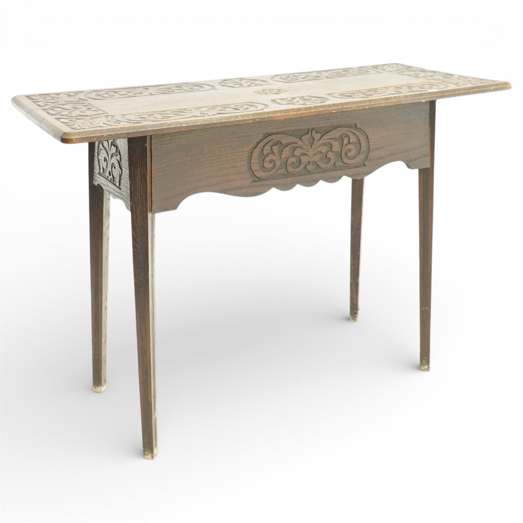 Arts and Crafts oak table, the rectangular top decorated with incised and carved scrolling foliage panels, the centre carved with a shield-shaped cartouche dated 1905, over a simple frieze with matching carved decoration to the front, on straight tapering legs