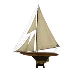 Early 20th century large pond yacht with mahogany hull, stained pine keel with brass rudder, simulated deck hatches and brass fittings, rigged as a staysail schooner (?) with four sails L117cm H148cm; loose mounted on stained pine stand