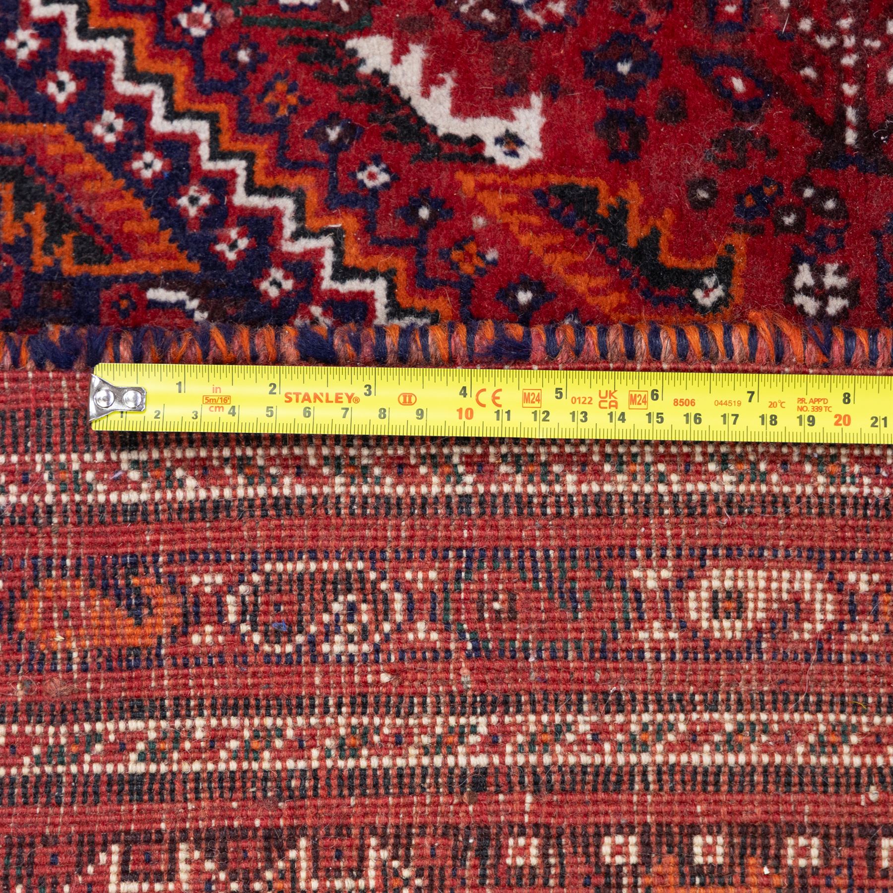 Qashqai wool carpet, red diamond-shaped field decorated with three stepped pole medallions, floral rosettes and scattered stylised motifs, within dark blue spandrels and multiple geometric guard borders