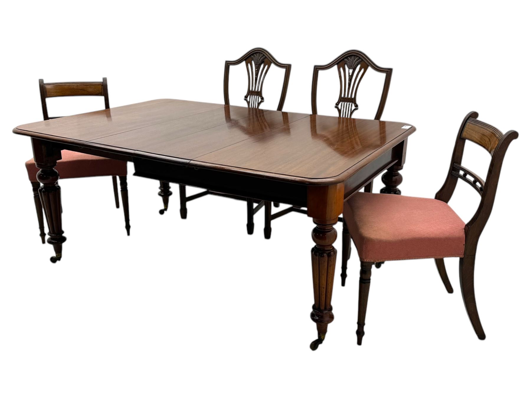 
Late Victorian mahogany extending dining table and four chairs, rectangular top with rounded corners and moulded edge, fitted with two additional leaves, raised on turned and reeded legs with brass castors, with a pair of Victorian mahogany hall chair, with curved top rail and plain splat, padded seat in textured salmon pink fabric, raised on turned and tapering front legs and another pair of early 20th century mahogany dining chair, with shield back and carved pierced splat, serpentine seat rail with striped upholstered cushion, raised on moulded square front legs