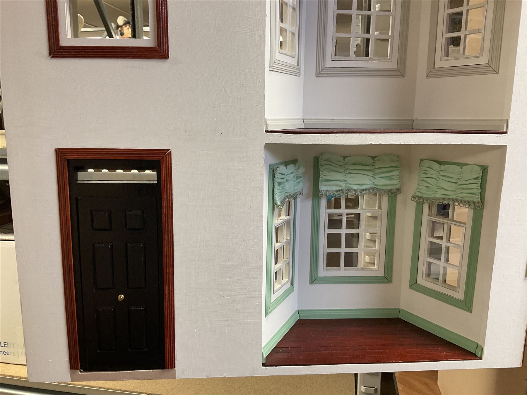 'The Hollies' - good quality sectional wooden doll's house in the form of a Georgian style four-storey bay windowed town house with simulated brick front elevation, rendered sides, off-set corner stonework, faux slate-hung top floor with flat roof and chimney stack, working sash windows, iron railings around front basement courtyard with hinged front elevation to two rooms with  spiral staircase, side hinged central section approached by external steps with iron balustrades to the sides leading to a front door, entrance hall with stairs to landing and two rooms on two floors with dado panelling and fire-surrounds, the top floor with top hung front elevation revealing stairs to a landing and bedroom; wired for electricity L51cm D65cm H107cm including chimney; together with a good quantity of quality wooden furniture and accessories including piano, dressers, bookcase and books, rugs, double half-tester bed, metalware, pictures etc