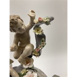 A Lladro mantel clock modelled as a globe with inset clock, surmounted by four putti and floral garlands, with blue printed mark and impressed 5973 beneath, H29cm.