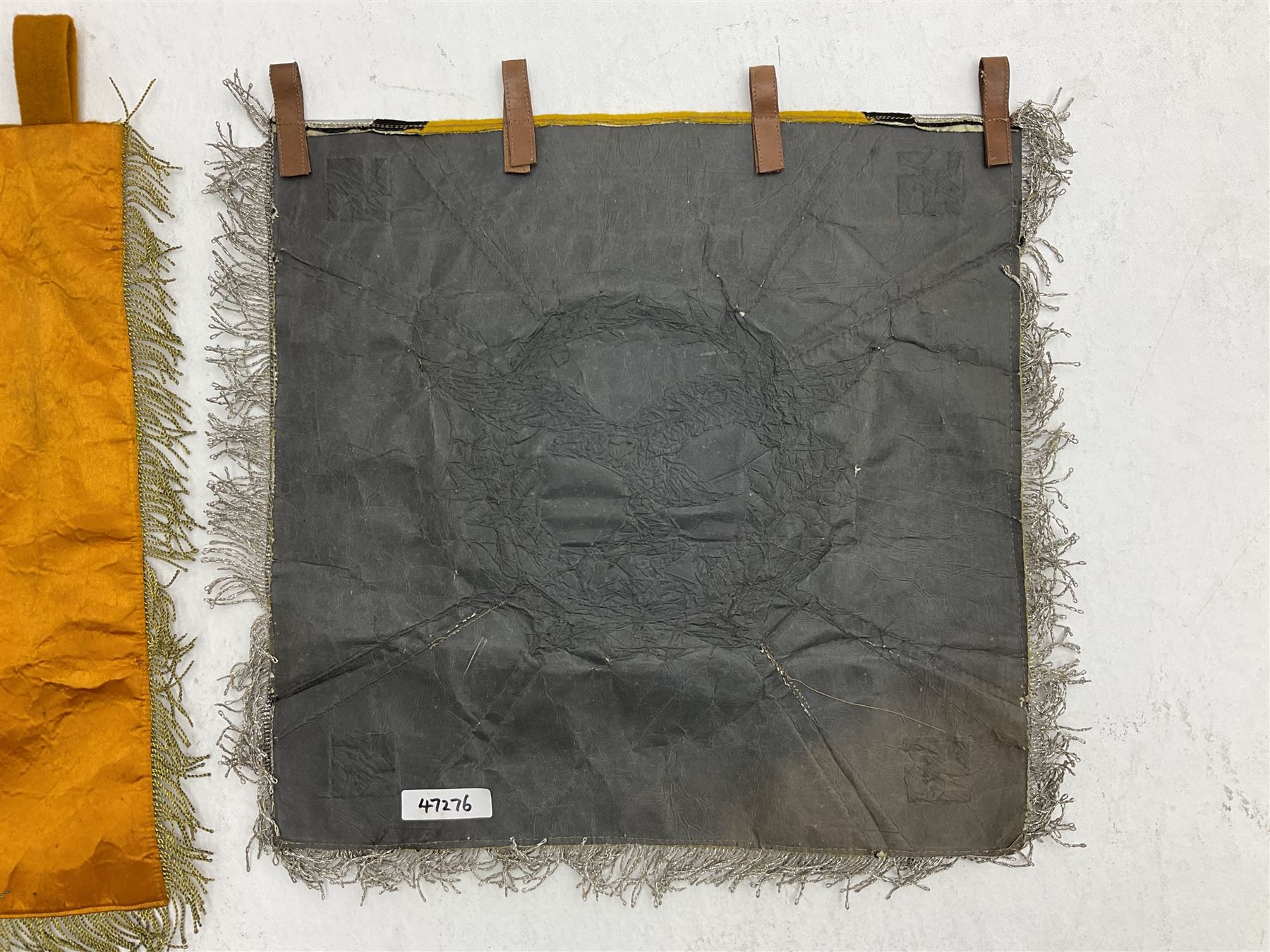Two replica German Luftwaffe trumpet banners, one heavily silver wire embroidered with Luftwaffe eagle in a wreath, on an amber, white and black rayed background, , with silver wire tasselled border and four leather hanging loops, approx. 50 x 49cm; the other slightly larger heavily gold wire embroidered with the Luftwaffe eagle on a plain amber ground with gold wire tasselled border and two hanging loops (2)