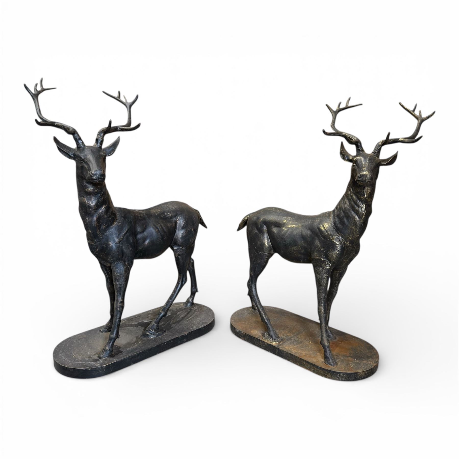 Pair of life-size cast iron garden or home stags, modelled standing upon oval plinths