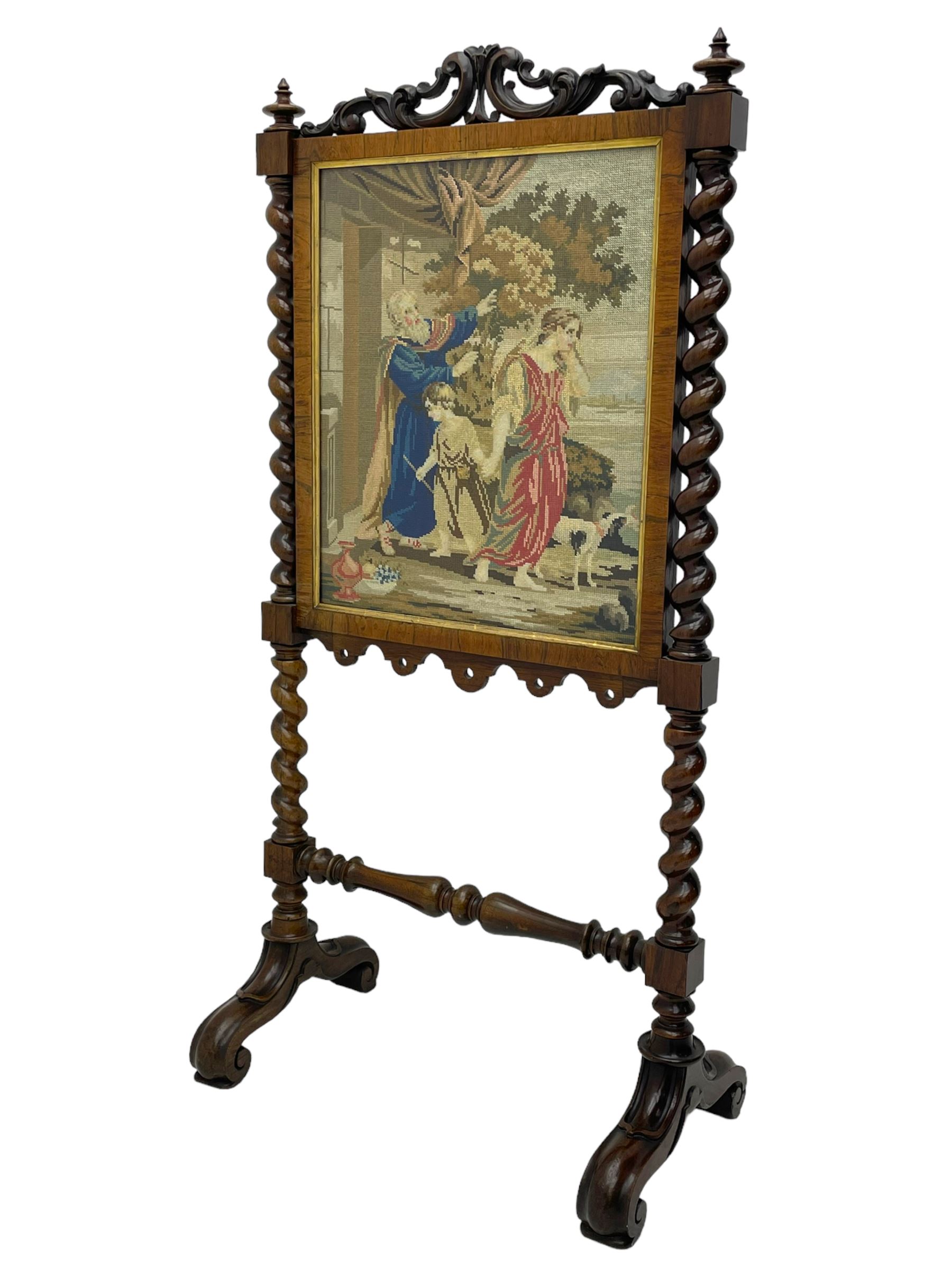 Victorian rosewood fire screen, scrolled foliage carved pediment, rectangular frame with moulded gilt slip enclosing figural needlework tapestry panel, on spiral turned supports with finials united by turned lower stretcher, on out-splayed feet with scroll carved terminals 