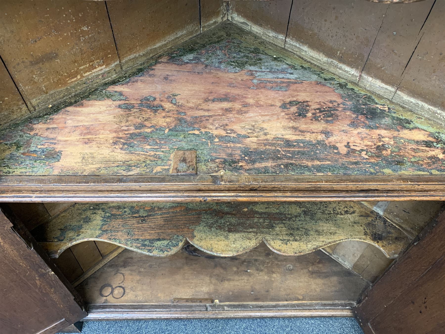 Large George III oak corner cupboard, projecting cornice over two stepped arch doors with fielded panels and blind fret work spandrels, flanked by fluted uprights, cupboard below enclosed by two fielded panel doors, the painted interior fitted with shaped shelves
 
