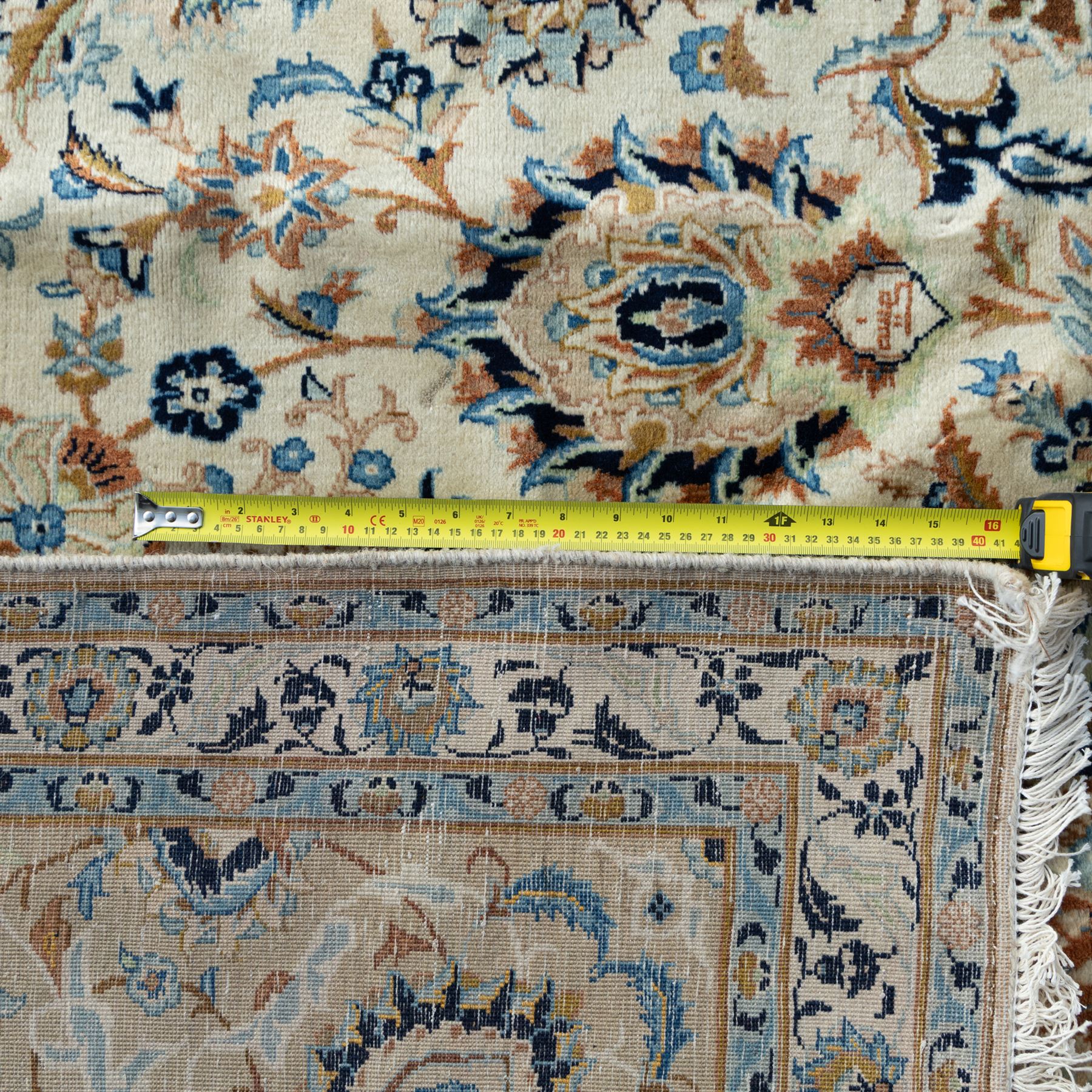 Central Persian Kashan rug, cream ground densely decorated with interconnected floral stems, rosettes and palmettes in shades of blue and gold, framed by layered foliate borders, woven in the Kashan region of Iran