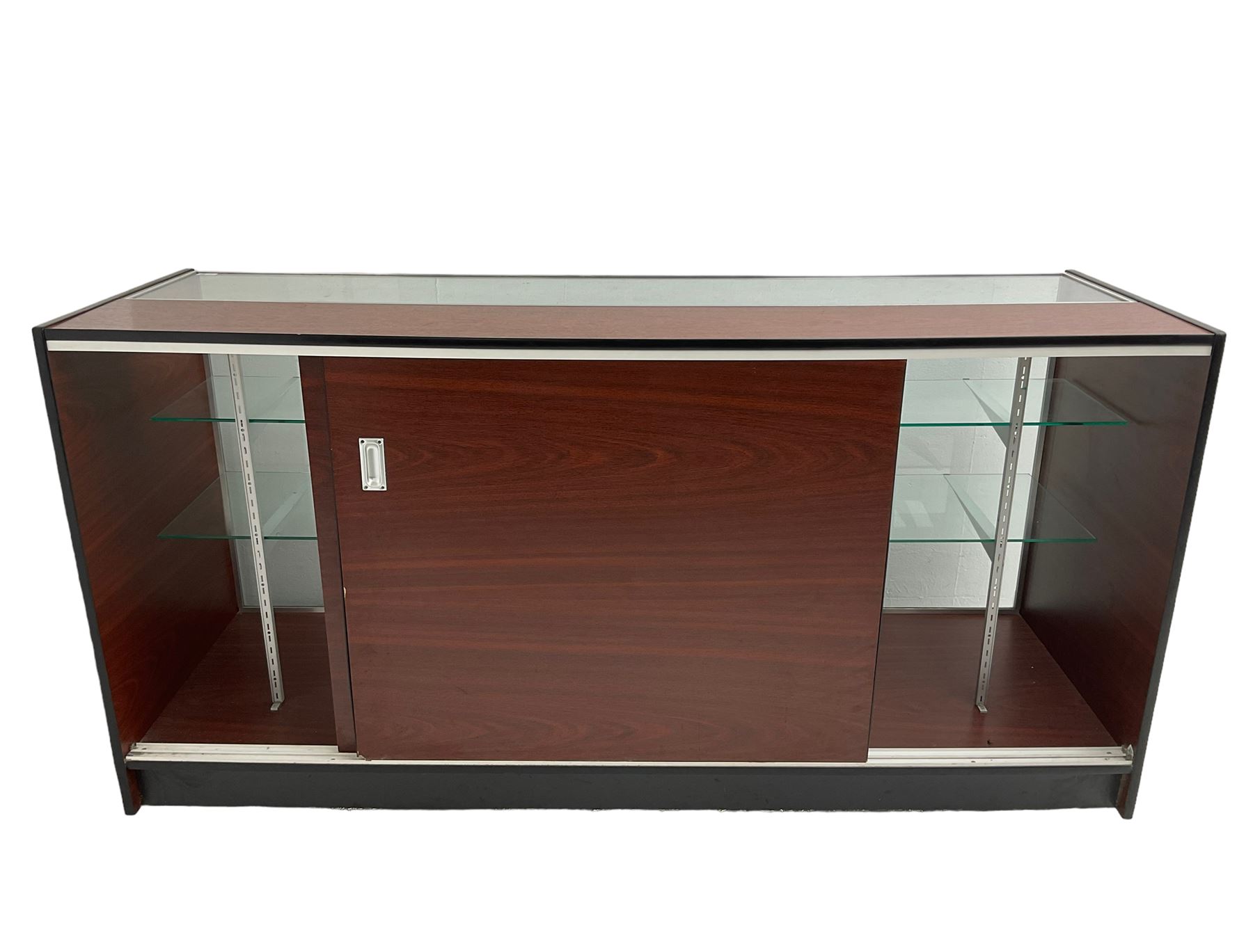 Shop display cabinet counter, glazed front and top, with mahogany laminate sides and back, enclosing two long adjustable shelves, fitted with two sliding cupboard doors to the rear, on castors