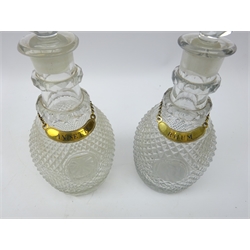  Pair matching Georgian hobnail cut decanters, ovoid form body, double cut neck-rings, central oval cartouche panel, one inscribed D the other vacant with late gilt metal labels 'Anisette' and 'Rhum' and two Victorian silver-plated knife rests   