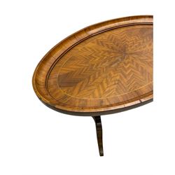 Early 20th century walnut coffee table, oval dished top with sunburst matched veneer, raised on twin cluster columns united by turned stretcher base on splayed supports