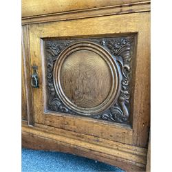 Late 19th century Arts & Crafts period oak mirror back sideboard, shaped bevelled mirror back carved with foliate scrolls and flower heads, down swept supports with elongated club-shaped uprights, moulded rectangular top over two drawers and three cupboards, the drawer fronts with copper handles decorated with sailing ships, panelled doors carved with mythical beasts, flowerheads and foliage, on moulded block feet