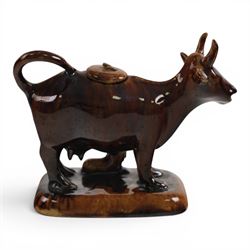 Three Staffordshire cow creamers, one with treacle glaze, the other two painted black and white with a seated figure of a milkmaid, H14cm