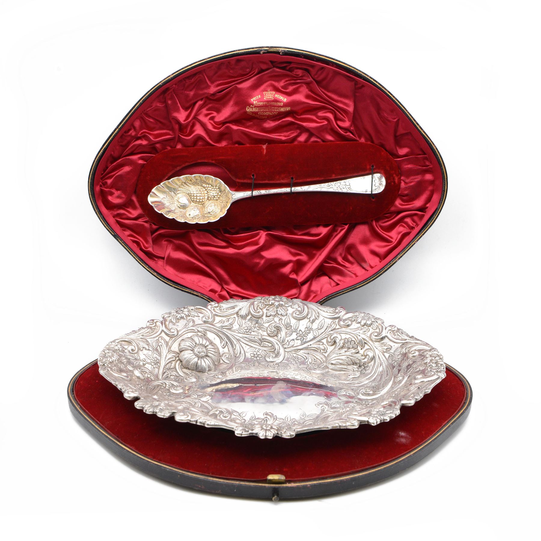 Victorian silver berry dish, of oval form, profusely embossed with floral and foliate decoration, hallmarked Goldsmiths & Silversmiths Co (William Gibson & John Lawrence Langman), London 1894, and a Victorian silver berry spoon, the gilt bowl embossed with berries, hallmarked London 1846, maker's mark worn and indistinct, contained within a tooled leather retailers case for Goldsmiths & Silversmiths London, both also with French weevil import marks, bowl end to end W27cm