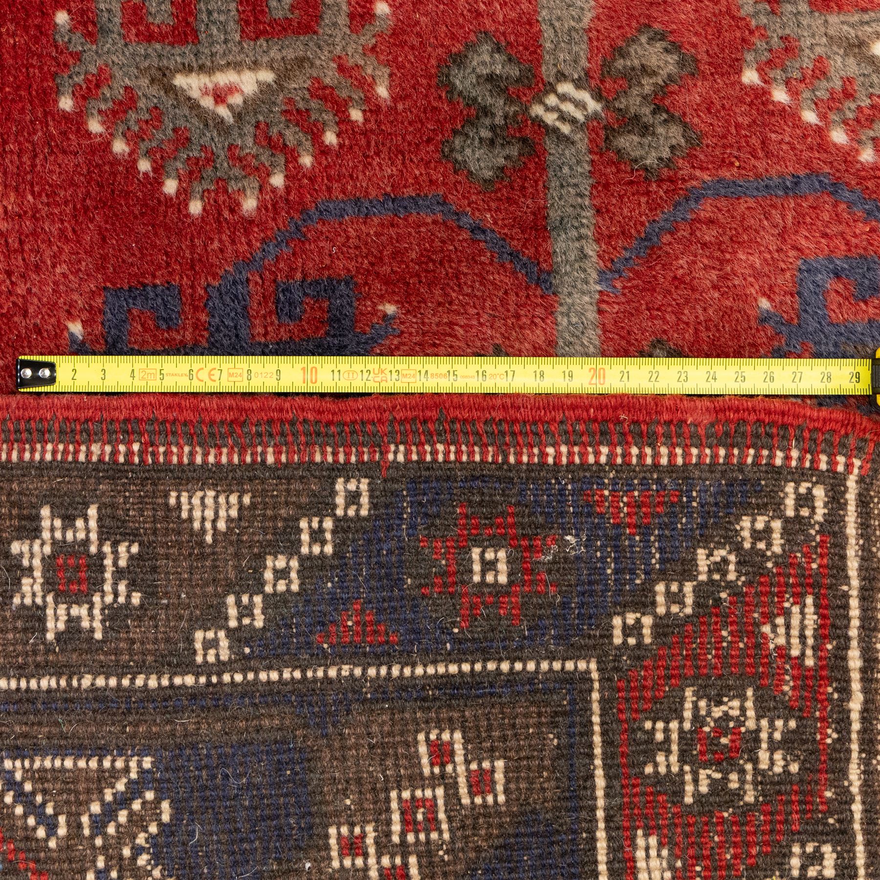 Caucasian Shirvan hand-knotted rug, red madder field with hooked lozenge medallions and stylized motifs, framed by ivory stepped spandrels and multiple geometric borders in indigo brown and ivory, with serrated palmettes and angular devices 